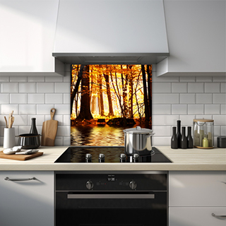 Wooded area by a river with orange sun shining through trees in an autumn setting glass splashback. thumbnail